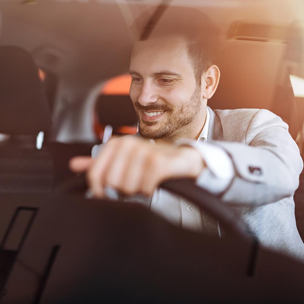 Ein Mann sitzt im PKW – er hat eine Anschlussgarantie für das Auto abgeschlossen