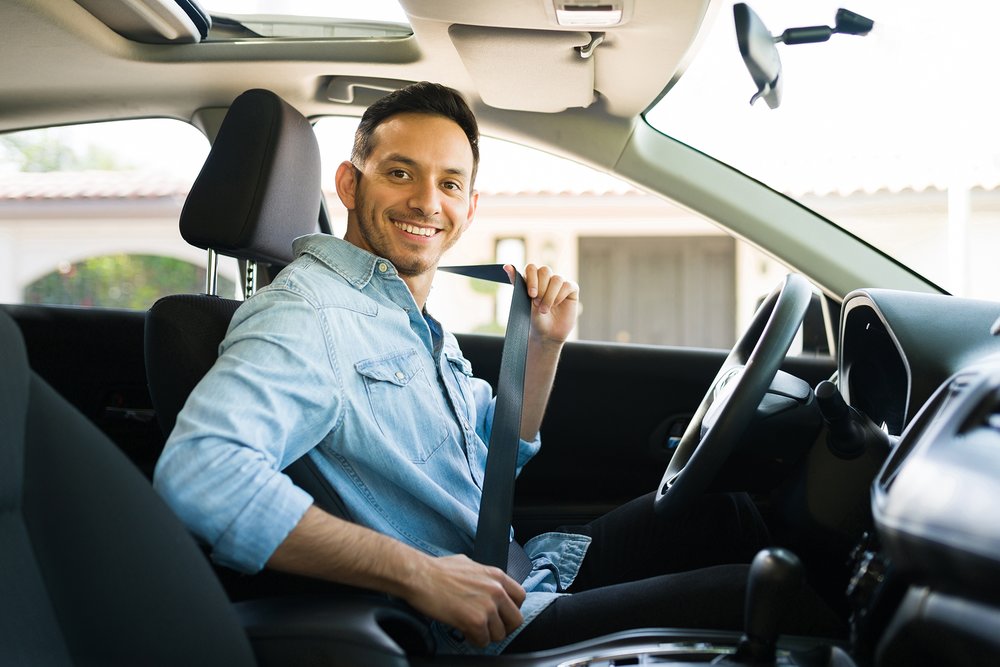Ein Mann sitzt glücklich im Auto; er fragte sich, ob eine Gebrauchtwagengarantie sinnvoll ist